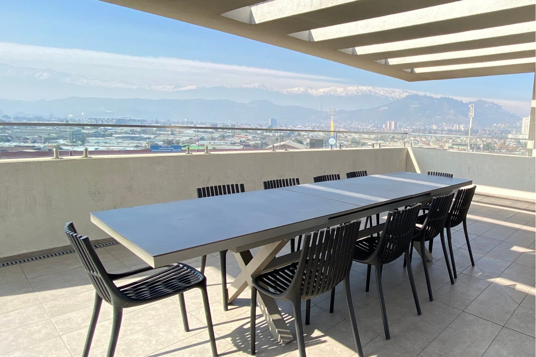 Terraza con mesa larga y vista a los cerros en Activa Plaza Chacabuco